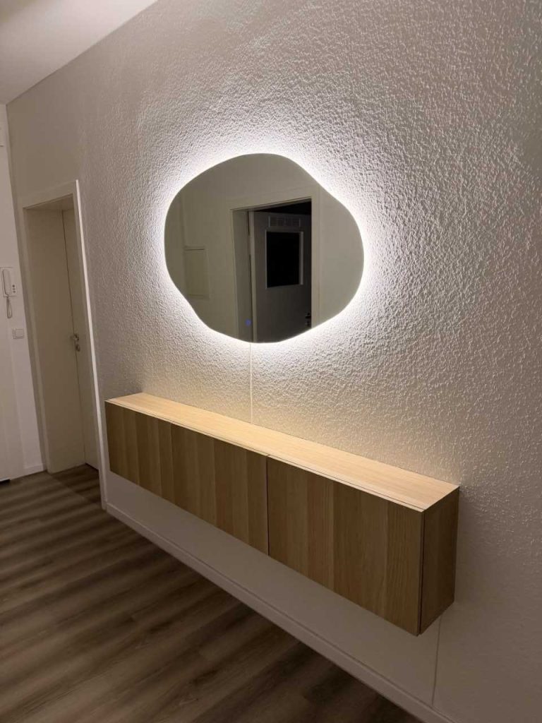 Lustro nieregularne LED Mirage z podświetleniem tylnym w przedpokoju, nad wiszącą komodą dębową
