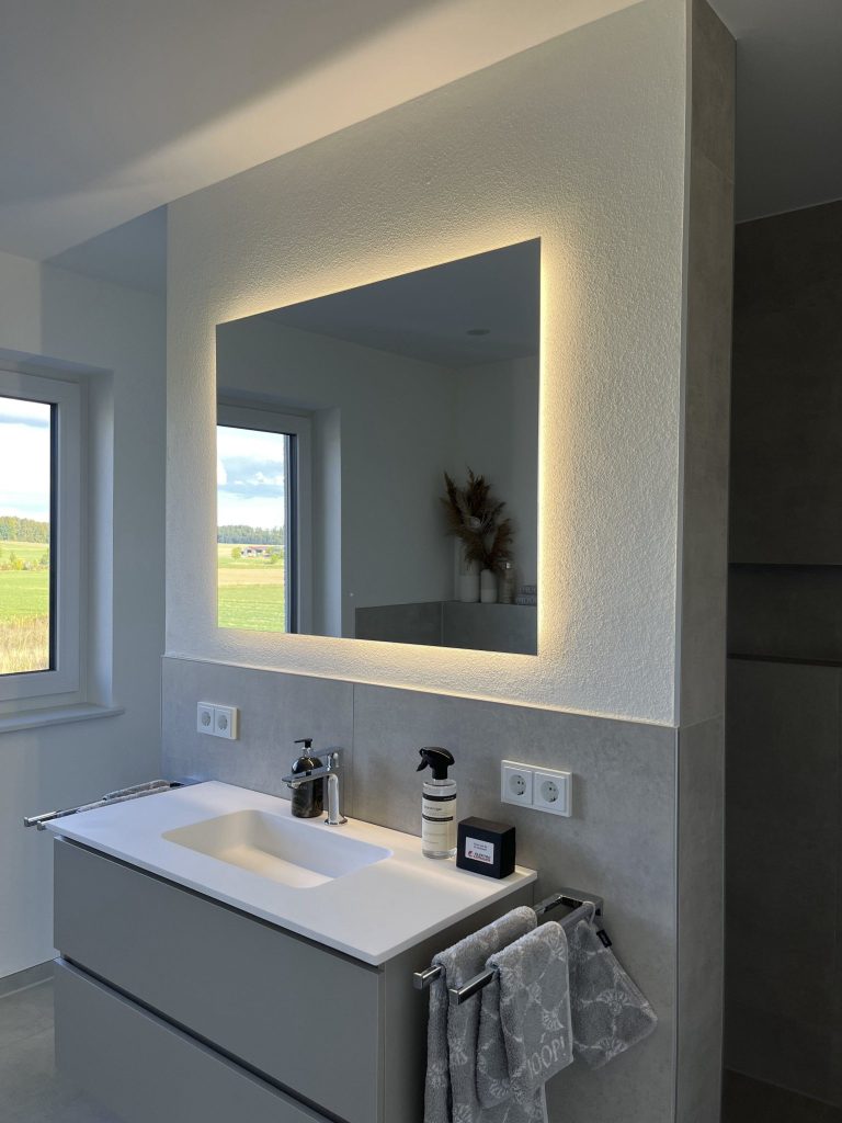 Prostokątne lustro LED Mirage z podświetleniem tylnym nad umywalką w jasnej łazience